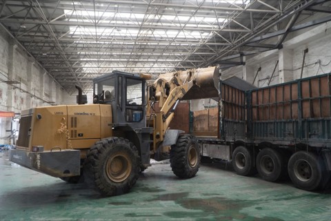Loader transferring material alongside a logistics truck