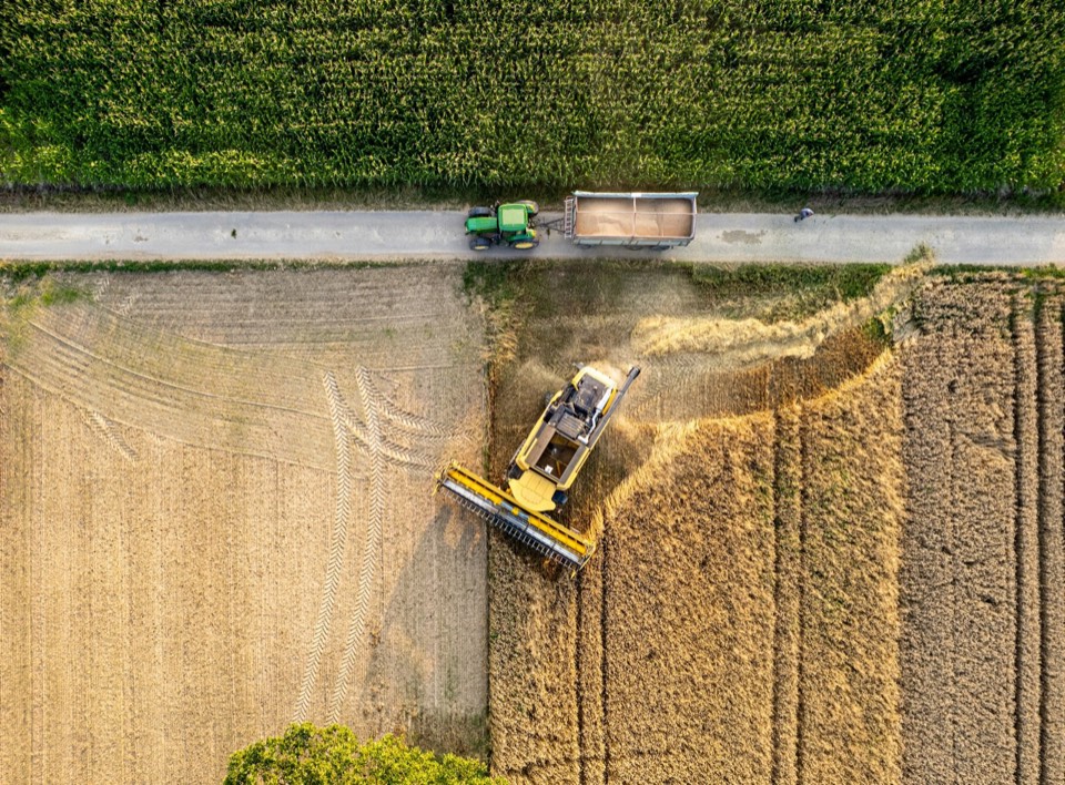Aerial view of a combine harvester working alongside a grain trailer