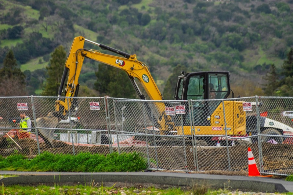 Excavator working on a fenced construction site